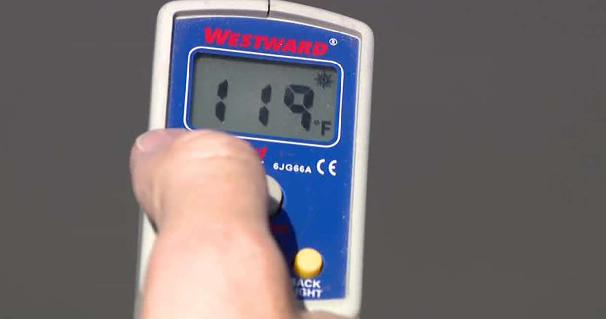 A KSL-TV crew uses an infrared thermometer to gauge surface temperatures in Salt Lake City Monday. Temperatures ranged from around 119 degrees for concrete, to 128 degrees for asphalt, and up to 140 degrees for metal surfaces.
