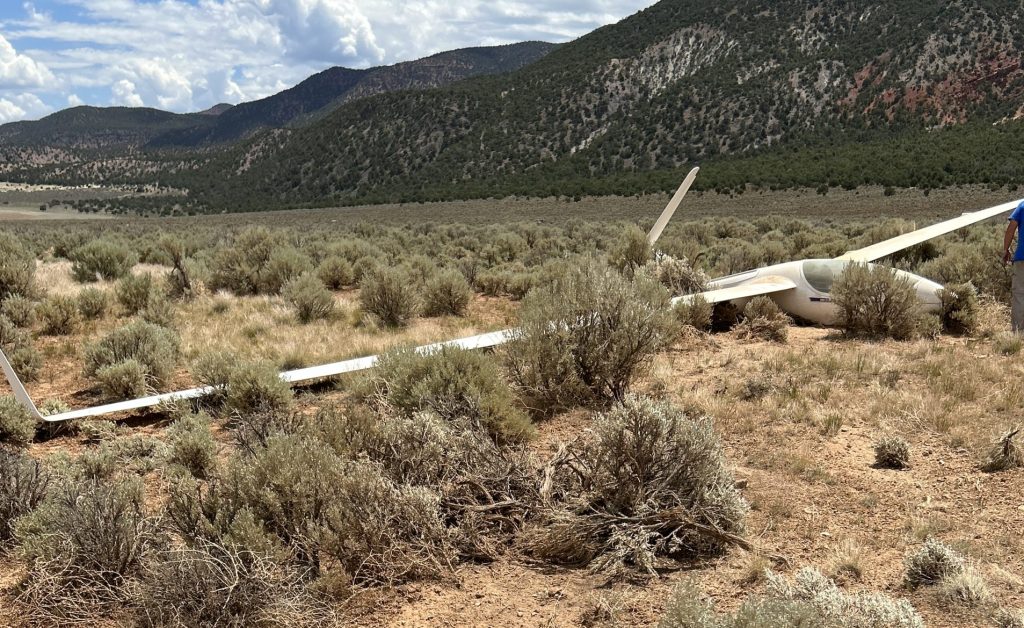 Authorities examine the wreckage of a glider whose pilot made a hard landing in a field near Parowan on Monday. The 74-year-old glider pilot escaped with minor injuries.