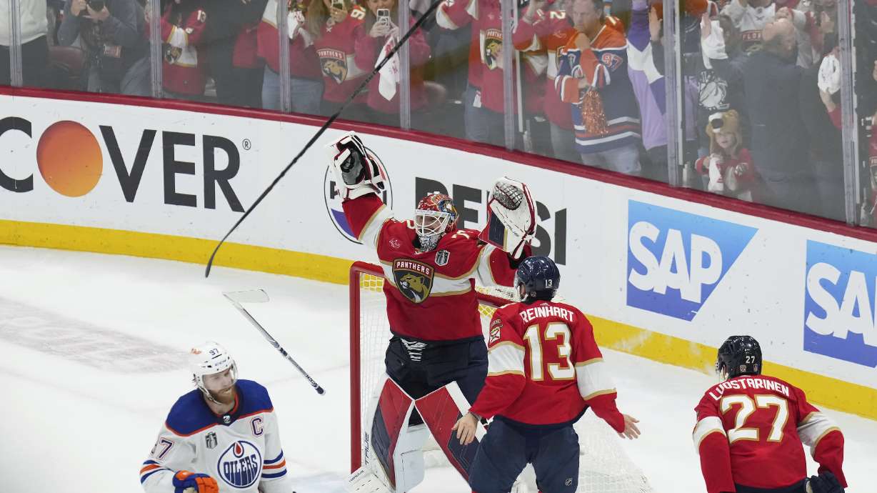 Florida Panthers goaltender Sergei Bobrovsky (72) and forward Sam Reinhart (13) celebrate after winning the NHL hockey Stanley Cup as Edmonton Oilers forward Connor McDavid (97) looks on after Game 7 of the Final in Sunrise, Fla., Monday, June 24, 2024.