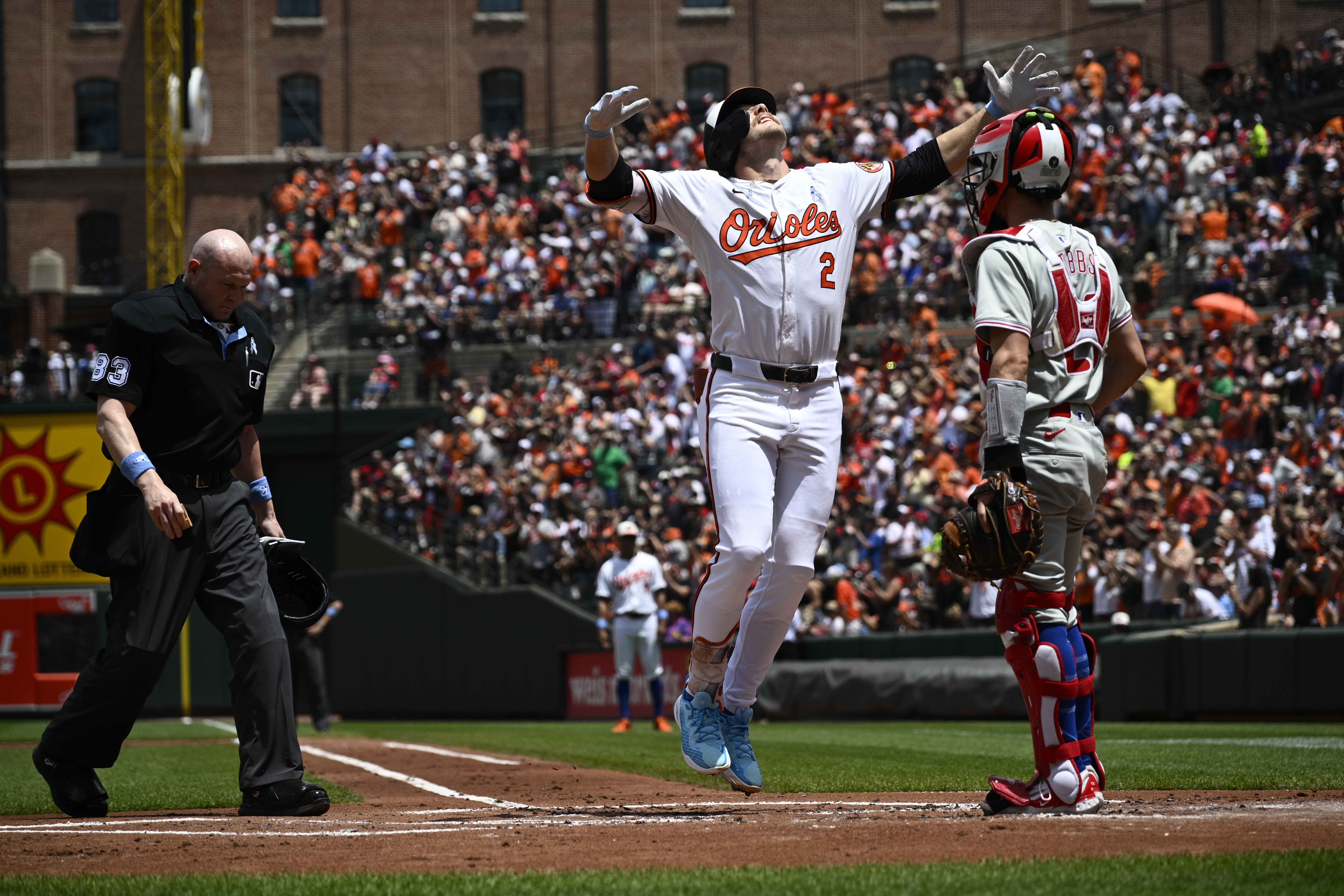 Baltimore Orioles' Gunnar Henderson (2) celebrates his home run in front of Philadelphia Phillies catcher Garrett Stubbs, right, during the first inning of a baseball game, Sunday, June 16, 2024, in Baltimore. Home plate umpire Mike Estabrook looks on at left. 