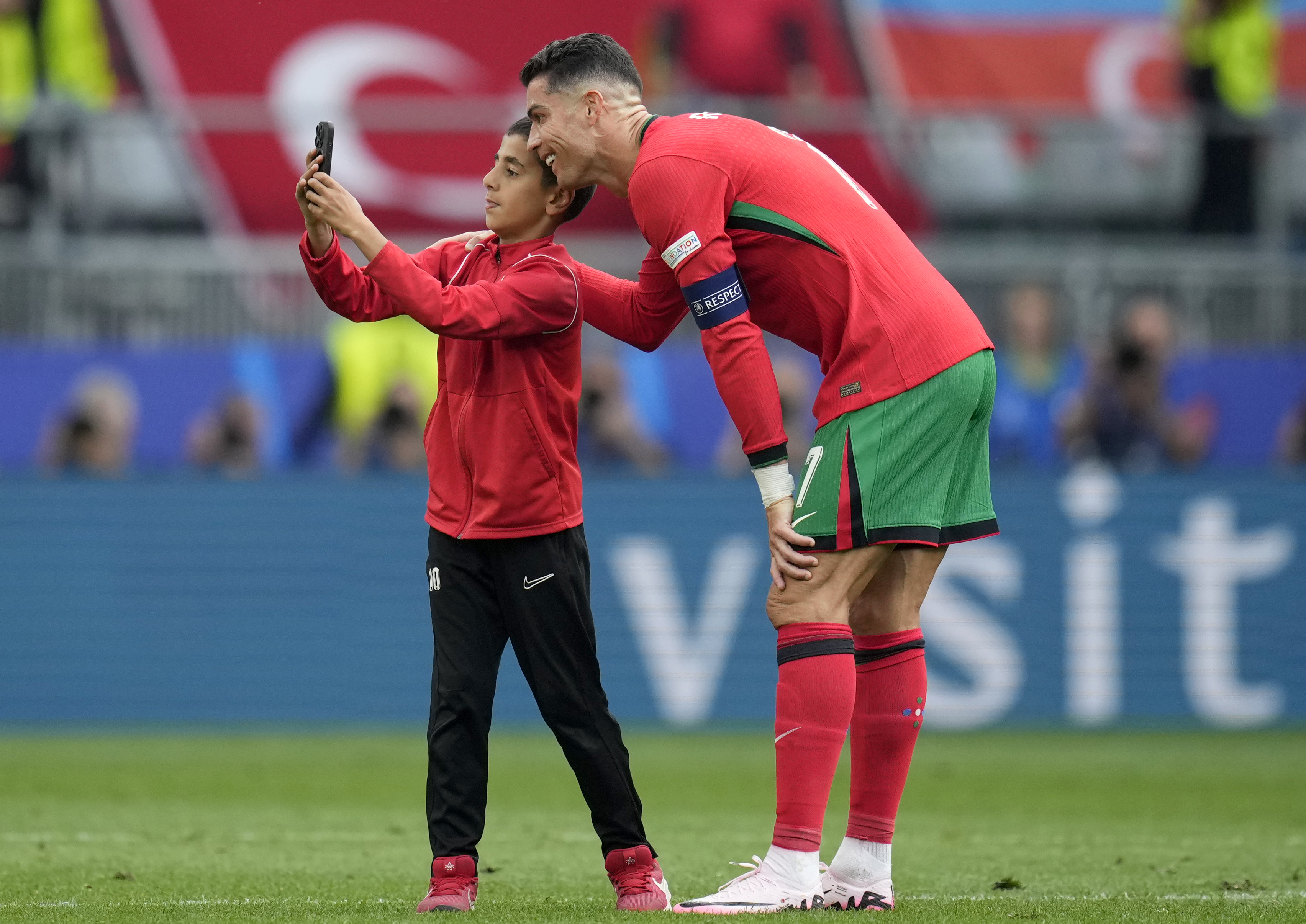 A young pitch invader takes a selfie with Portugal's Cristiano Ronaldo during a Group F match between Turkey and Portugal at the Euro 2024 soccer tournament in Dortmund, Germany, Saturday, June 22, 2024. 