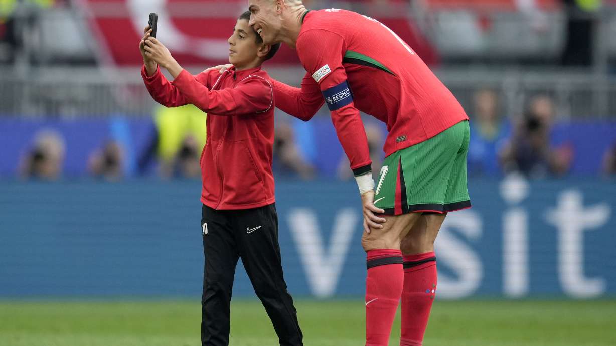 A young pitch invader takes a selfie with Portugal's Cristiano Ronaldo during a Group F match between Turkey and Portugal at the Euro 2024 soccer tournament in Dortmund, Germany, Saturday, June 22, 2024.
