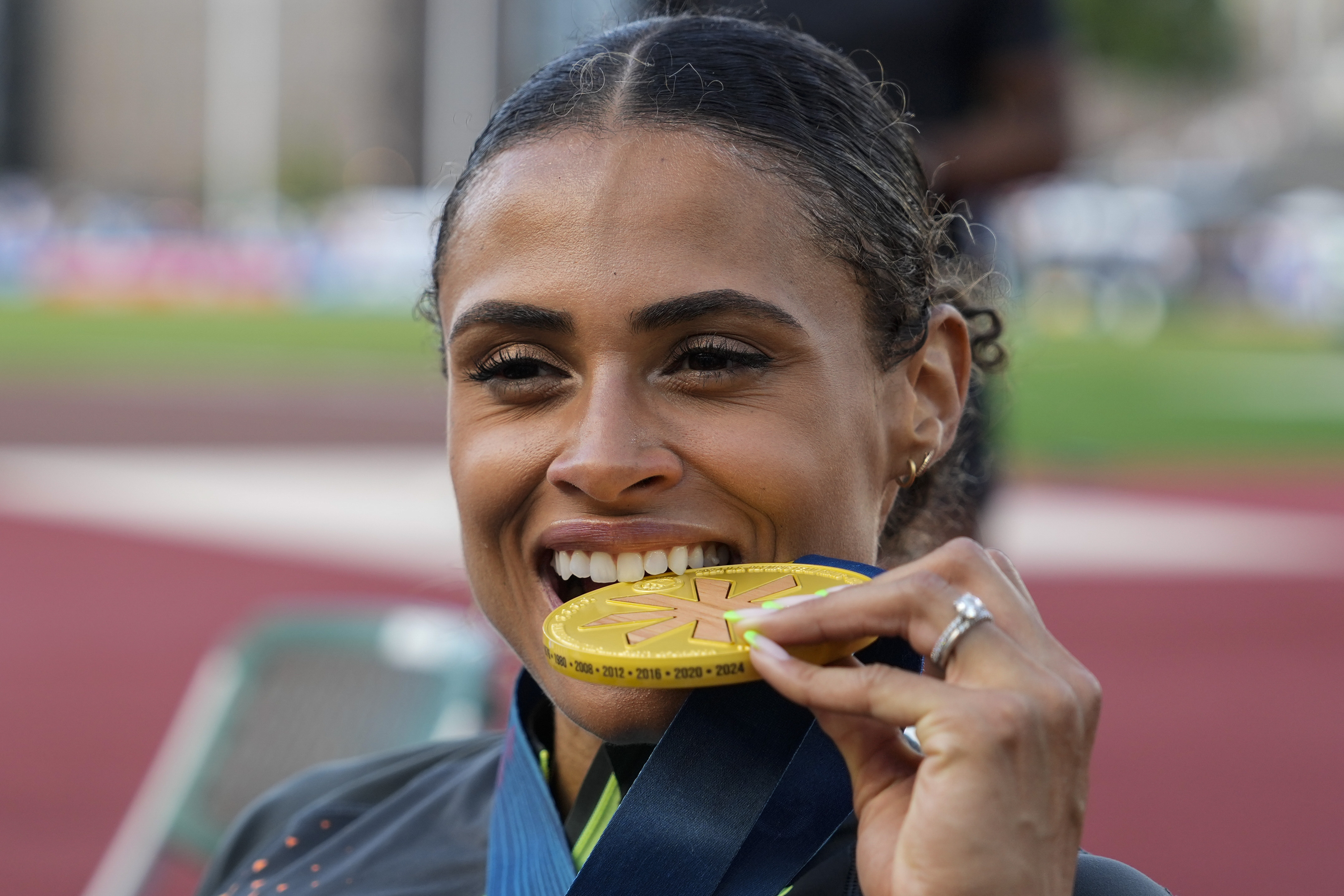 Sydney McLaughlin-Levrone bites down on her gold medal after winning the women's 400-meter hurdles final during the U.S. Track and Field Olympic Team Trials, Sunday, June 30, 2024, in Eugene, Ore. 