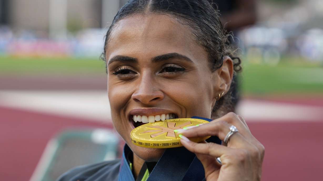 Sydney McLaughlin-Levrone bites down on her gold medal after winning the women's 400-meter hurdles final during the U.S. Track and Field Olympic Team Trials, Sunday, June 30, 2024, in Eugene, Ore.