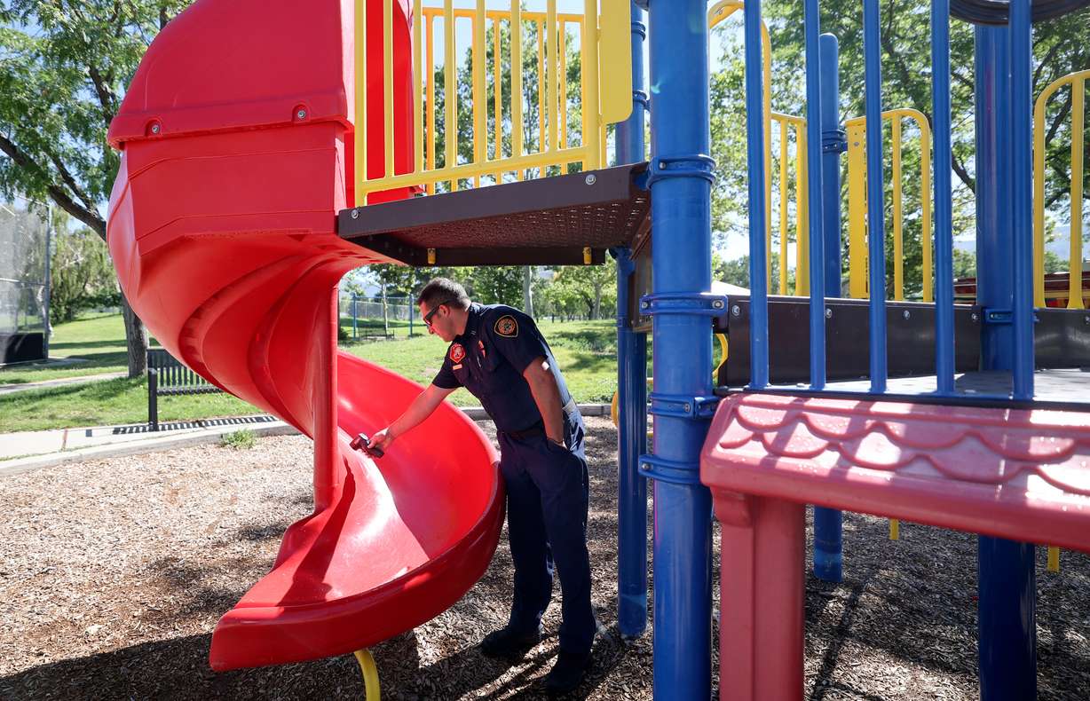 Salt Lake City Fire Capt. Brandt Hancuff measures the temperature of a slide during a press conference at Sunnyside Park in Salt Lake City on Tuesday. The slide surface measured 97 degrees when air temperature was 71 degrees.