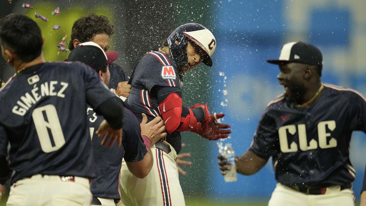 Cleveland Guardians' Bo Naylor, center, is mobbed by teammates after hitting a sacrifice fly to score Andres Gimenez in the ninth inning to defeat the Chicago White Sox in a baseball game Tuesday, July 2, 2024, in Cleveland.