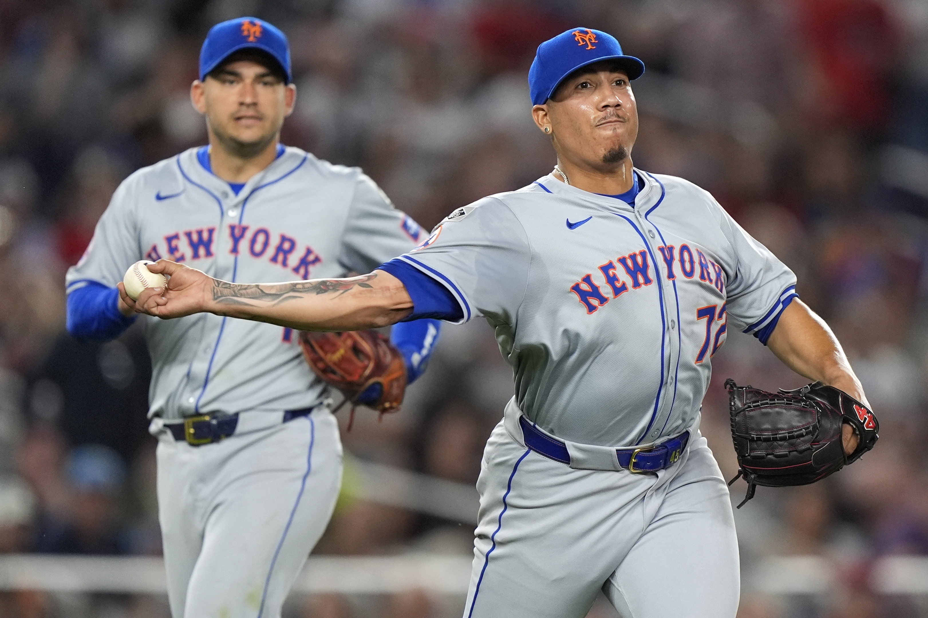 New York Mets pitcher Dedniel Nunez, right, throws an infield ground ball to first base ahead of second baseman Jose Iglesias, left, during the eighth inning of a baseball game against the Washington Nationals at Nationals Park, Monday, July 1, 2024, in Washington.