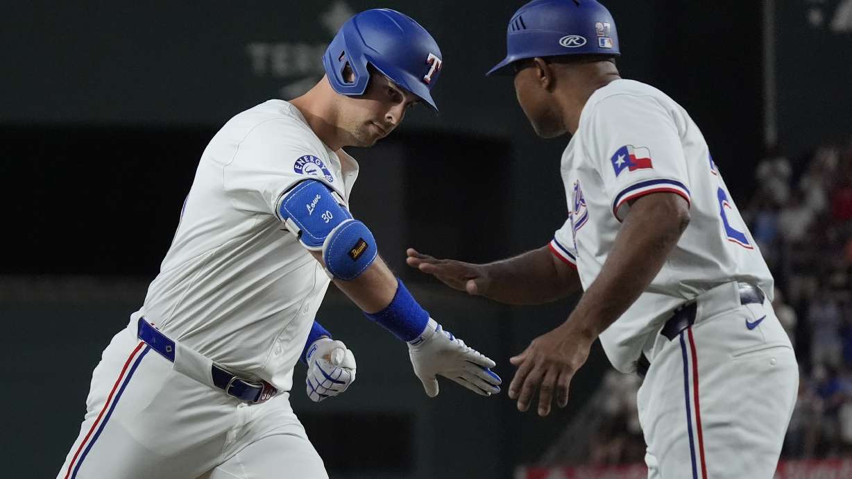 Texas Rangers Nathaniel Lowe, left, is congratulated by third base coach Tony Beasley (27) as Lowe rounds the bases after hitting a home run during the first inning of a baseball game against the San Diego Padres in Arlington, Texas, Tuesday, July 2, 2024. Rangers Josh Smith also scored on the play.