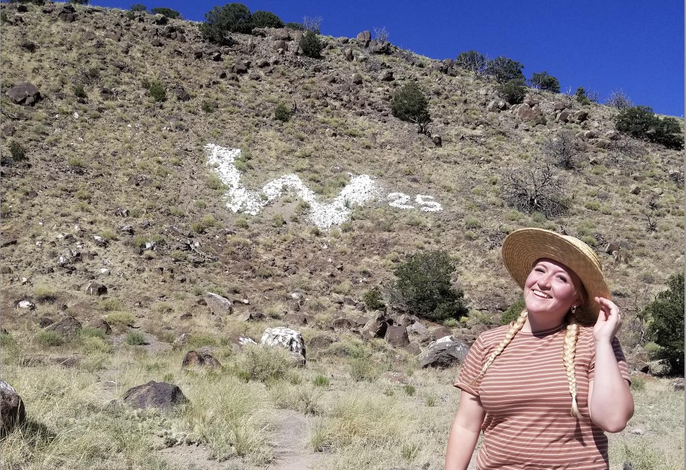 Erica Lewis Bradshaw poses with the Wayne County "W" in Bicknell. Bradshaw has hiked 77 of 83 mountainside letters in Utah.