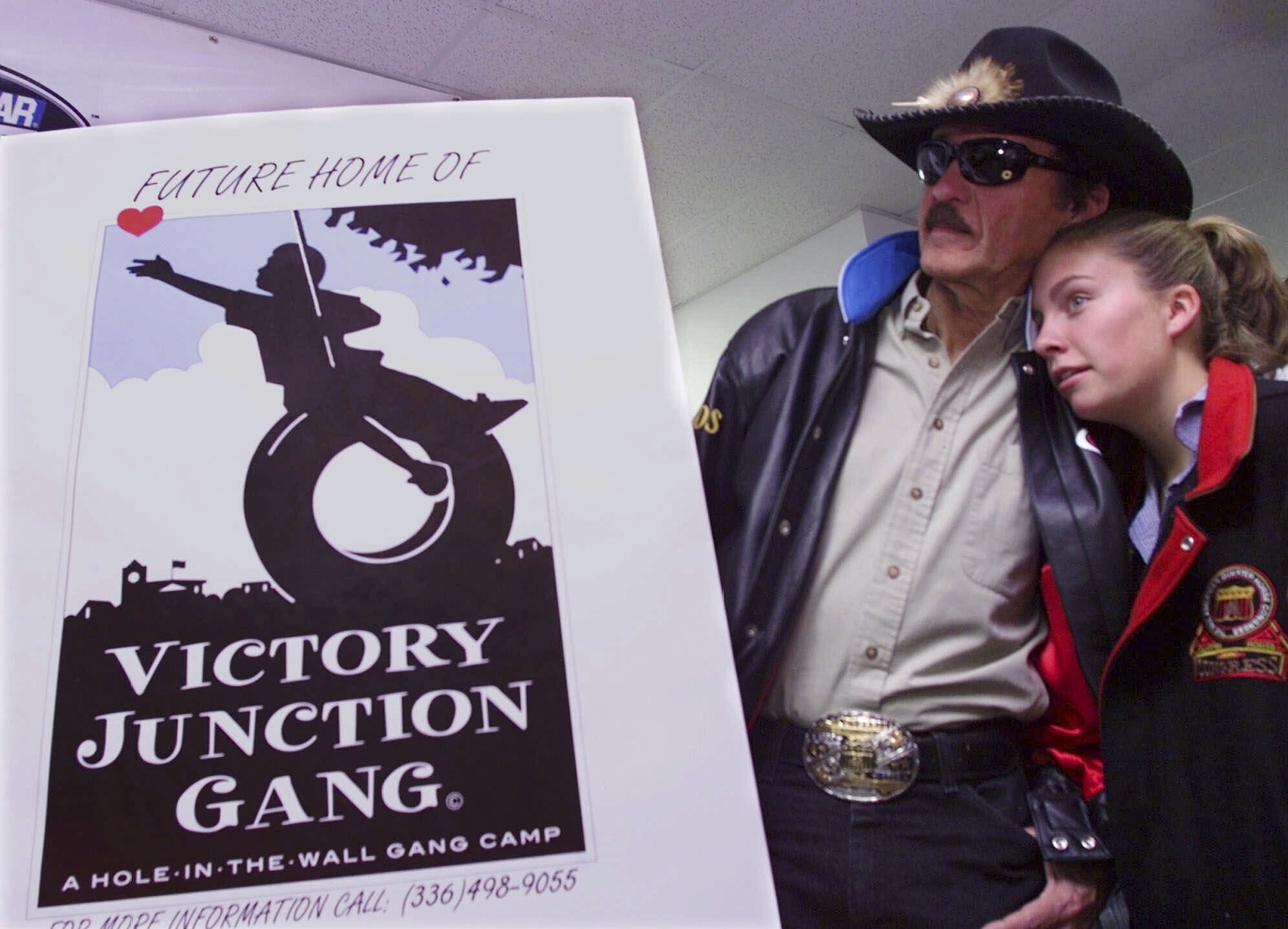 FILE - Montgomery Lee Petty, 14, leans on her grandfather, racing great Richard Petty, as she listens to her dad Kyle Petty, not shown, announce that the Petty family is founding The Victory Junction Gang Camp during a news conference at the North Carolina Speedway near Rockingham, N.C., Saturday, Oct. 21, 2000. Adam Petty was 19 when he was killed in a crash practicing for a race at New Hampshire. Not too many years before, he'd made a visit to Paul Newman's-owned Camp Boggy Creek and became transfixed in creating a similar camp in North Carolina for children with serious medical issues. Richard Petty said the family following through on Adam's dream with be their lasting legacy.