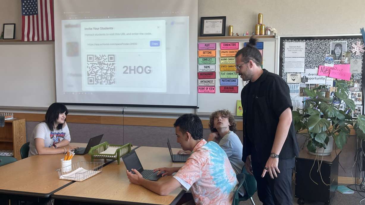 Graham Bany, an English teacher and digital technology coach at Valley High School, talks to students as they work through an assignment using SchoolAI's software.