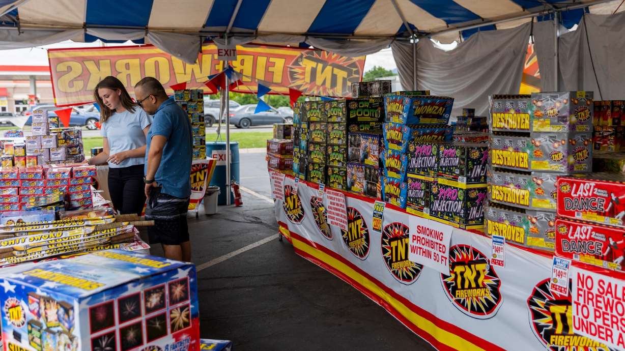 Karlie Roberts sells fireworks to Sam Khadka at a TNT tent selling fireworks on Redwood Road in Salt Lake City on Monday. High prices and return of commercial displays have dampened the fuse for many consumers.