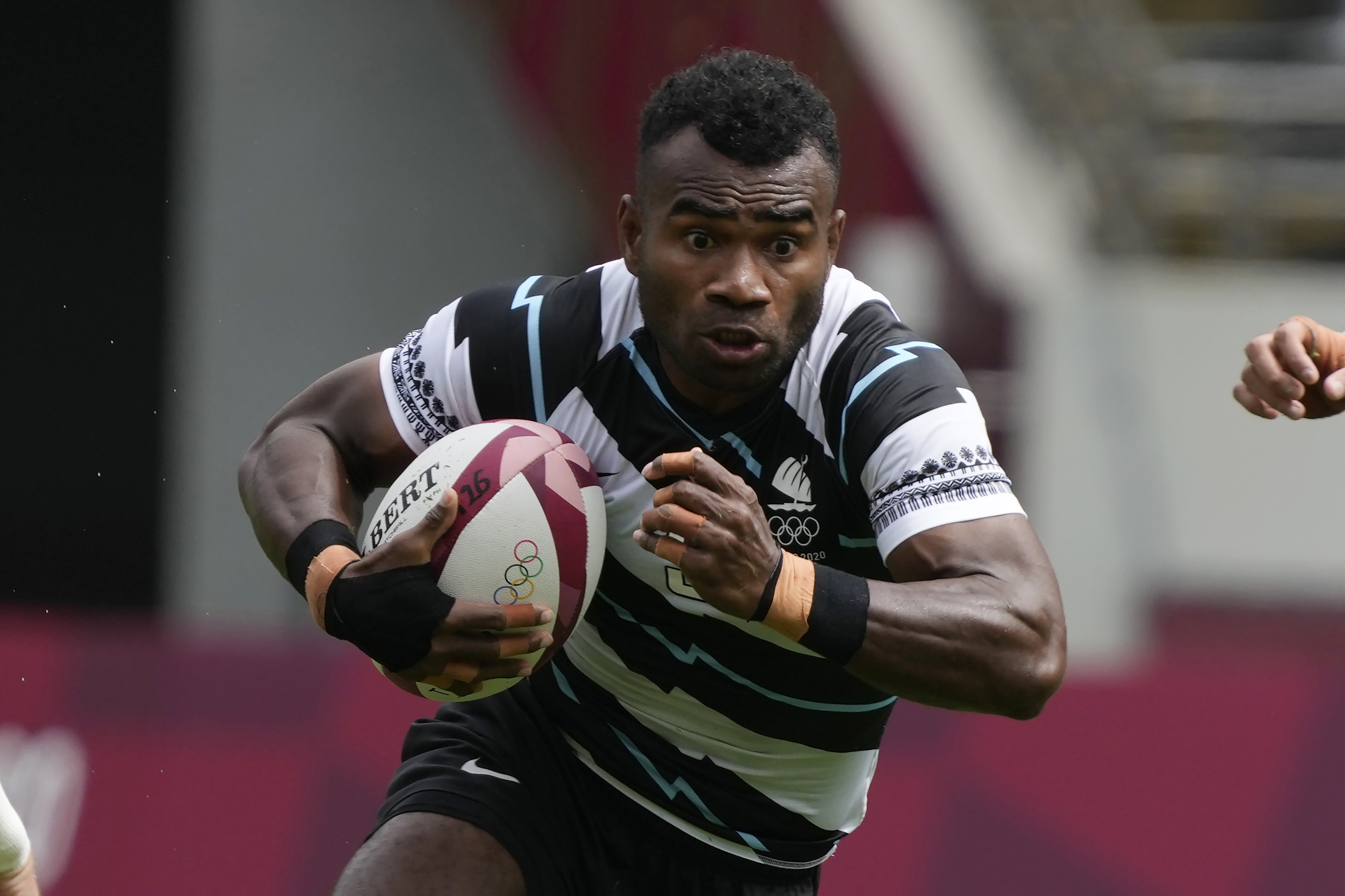 FILE - Fiji's Jerry Tuwai, center, evades Britain's Alex Davis as Fiji's Meli Derenalagi looks on, in their men's rugby sevens match at the 2020 Summer Olympics, on July 27, 2021 in Tokyo, Japan. Osea Kolinisau led Fiji to its first ever Olympic gold medal when rugby sevens made its debut at the Summer Games in 2016 and now, as a coach, he’s turning to old teammate Jerry Tuwai to help the Pacific nation’s bid for a three-peat. 