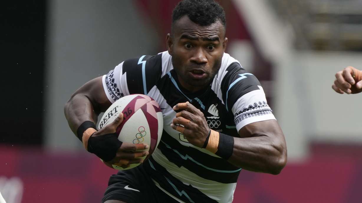 FILE - Fiji's Jerry Tuwai, center, evades Britain's Alex Davis as Fiji's Meli Derenalagi looks on, in their men's rugby sevens match at the 2020 Summer Olympics, on July 27, 2021 in Tokyo, Japan. Osea Kolinisau led Fiji to its first ever Olympic gold medal when rugby sevens made its debut at the Summer Games in 2016 and now, as a coach, he’s turning to old teammate Jerry Tuwai to help the Pacific nation’s bid for a three-peat.