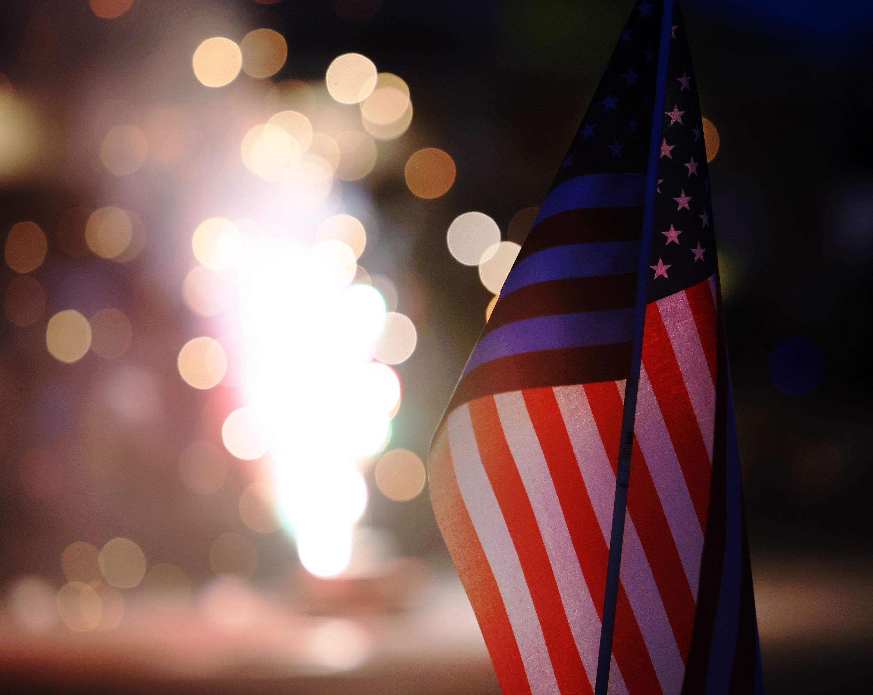 A small American flag is illuminated by fireworks on July 4, 2022. Explore where your family will attend fireworks to celebrate America's 250th birthday.