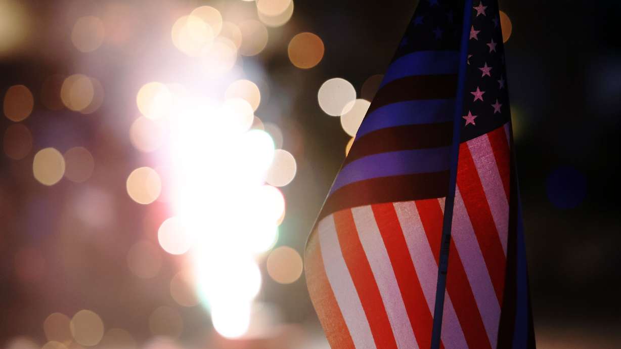 A small American flag is illuminated by fireworks on July 4, 2022. Explore where your family will attend fireworks to celebrate America's 250th birthday.