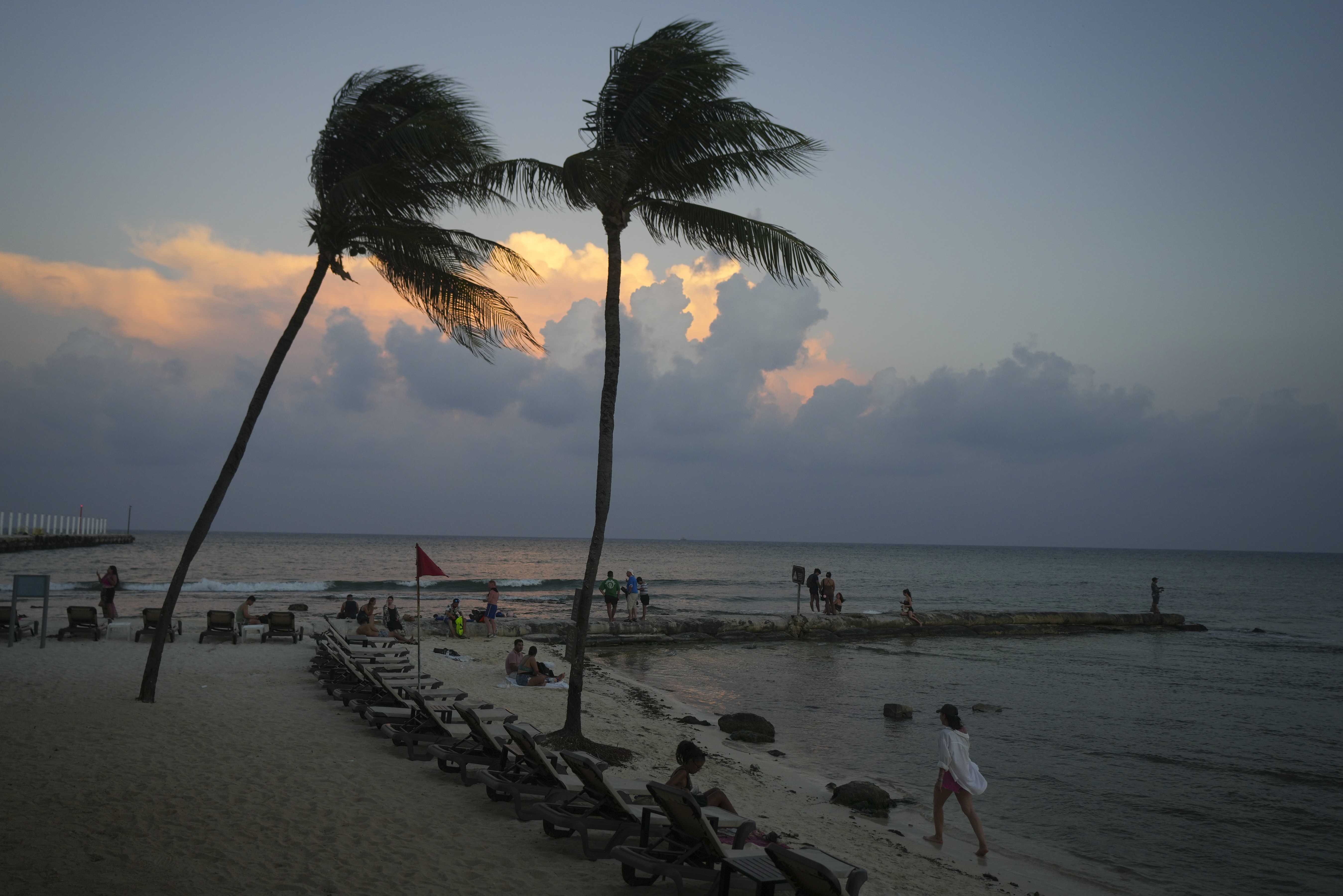 People lounge on the beach as the sun sets ahead of Hurricane Beryl's expected arrival, in Playa del Carmen, Mexico, Wednesday.