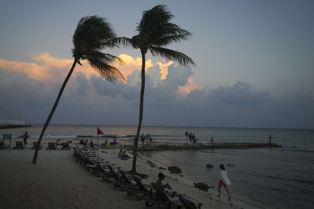 People lounge on the beach as the sun sets ahead of Hurricane Beryl's expected arrival, in Playa del Carmen, Mexico, Wednesday.