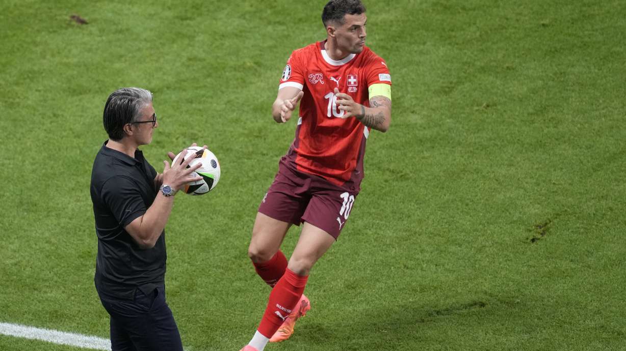 Switzerland's head coach Murat Yakin holds a ball ahead of Switzerland's Granit Xhaka prior a Group A match between Switzerland and Germany at the Euro 2024 soccer tournament in Frankfurt, Germany, Sunday, June 23, 2024.