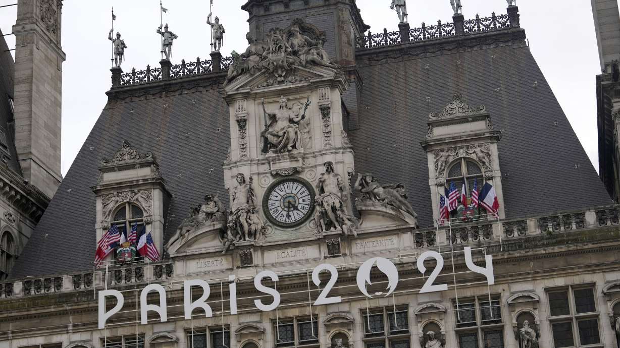 The logo of the Paris 2024 Olympic Games hangs from the facade of the Paris city hall, Wednesday, July 3, 2024 in Paris. Just three weeks before the Olympics, the excitement that was building up in the host city has mingled with anxiety about France’s political future.