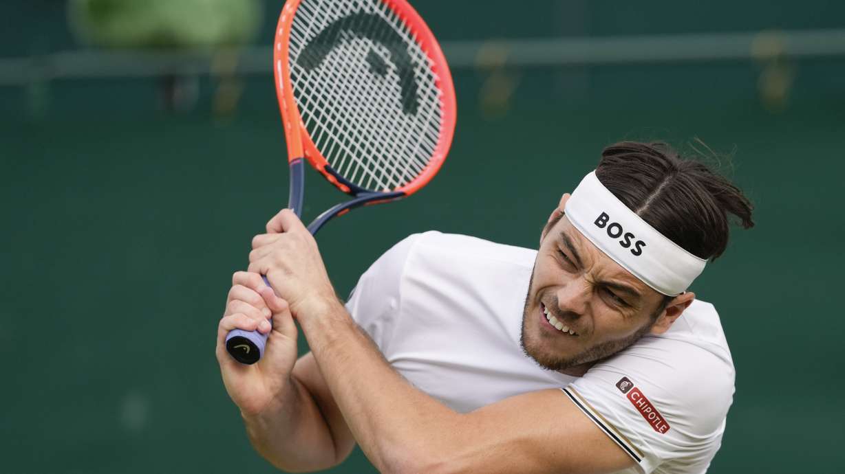 Taylor Fritz of the United States plays a backhand return to Arthur Rinderknech of France during their second round match at the Wimbledon tennis championships in London, Thursday, July 4, 2024.