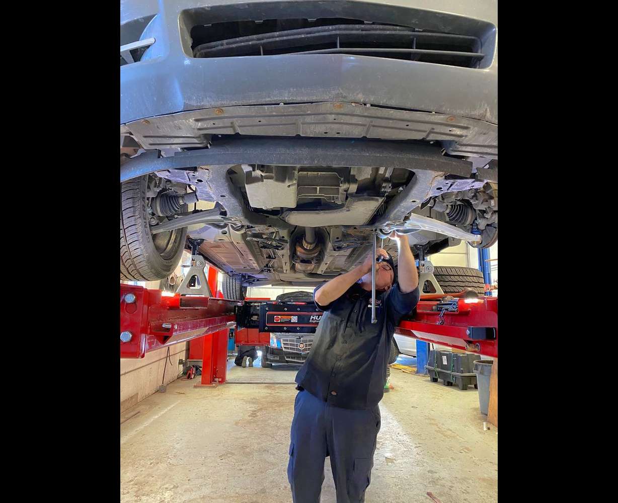 At one of the Clegg Auto stores, a mechanic works on the undercarriage of a vehicle.