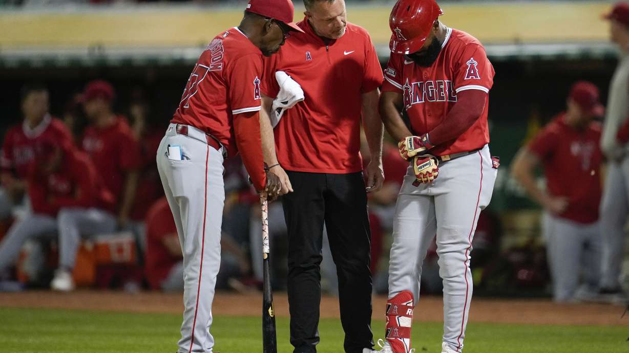 Los Angeles Angels' Luis Rengifo, right, holds his arm during the ninth inning of a baseball game against the Oakland Athletics, Wednesday, July 3, 2024, in Oakland, Calif. Rengifo left the game with an injury.
