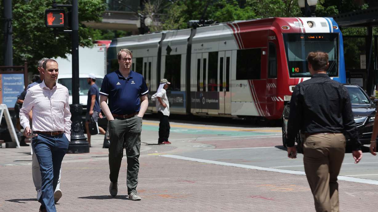 Pedestrians walk on Main Street as a TRAX train goes by in Salt Lake City on May 31, 2023. Utah Transit Authority said it will not collect fares between Friday and Sunday this week as it upgrades its fare collection system.