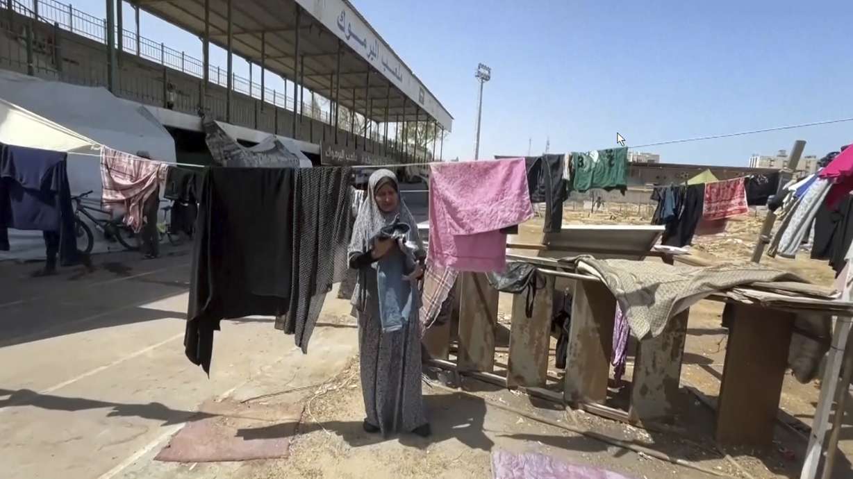 This image from video shows a woman drying clothes, Friday, July 5, 2024 in Gaza City, Gaza Strip. Yarmouk Sports Stadium, once Gaza's biggest soccer arena, is now sheltering thousands of displaced Palestinians who are scraping by with little food or water.