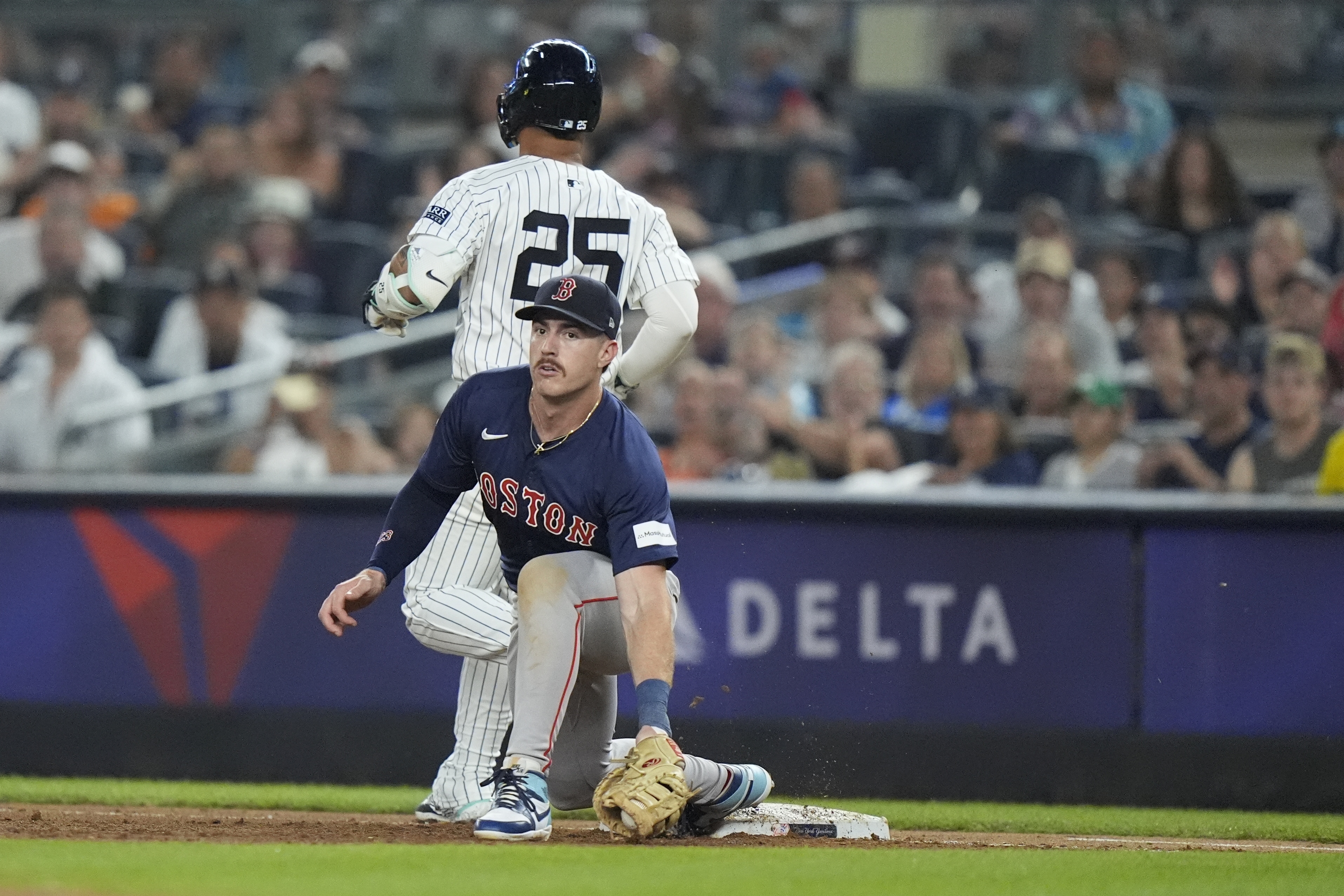 New York Yankees' Gleyber Torres (25) runs past Boston Red Sox's Romy Gonzalez, bottom, for a single during the fourth inning of a baseball game, Friday, July 5, 2024, in New York. Torres was injured on the play. 