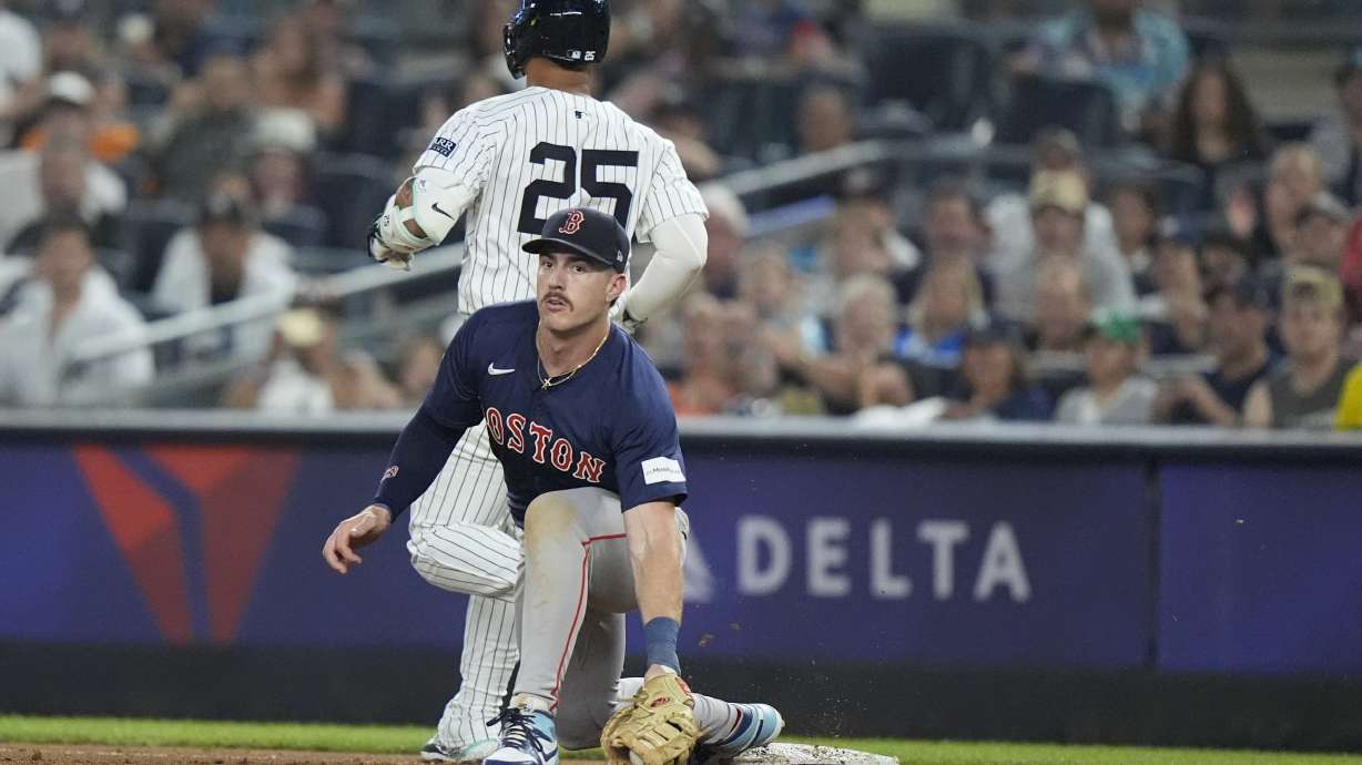 New York Yankees' Gleyber Torres (25) runs past Boston Red Sox's Romy Gonzalez, bottom, for a single during the fourth inning of a baseball game, Friday, July 5, 2024, in New York. Torres was injured on the play.