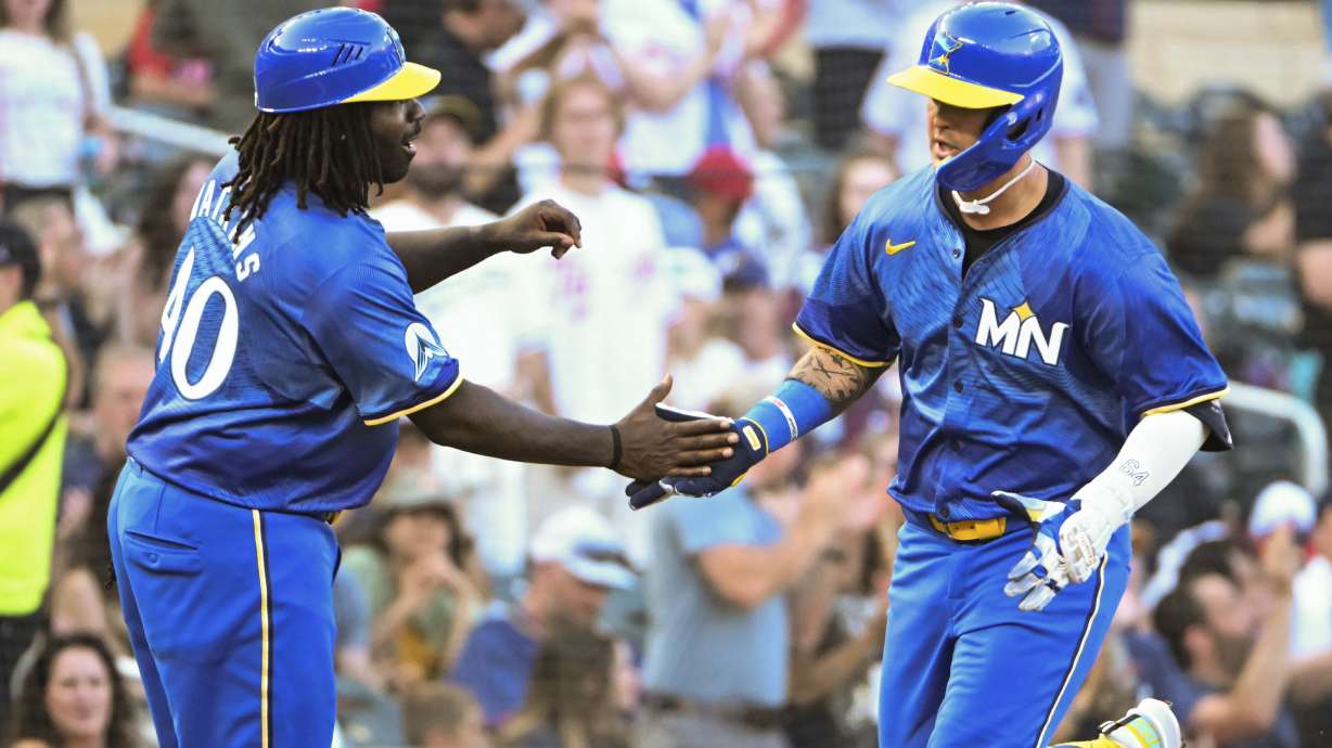 Minnesota Twins' Jose Miranda, right, celebrates with third base coach Tommy Watkins, left, after hitting a home run off Houston Astros starting pitcher Shawn Dubin during the third inning of a baseball game Friday, July 5, 2024, in Minneapolis.