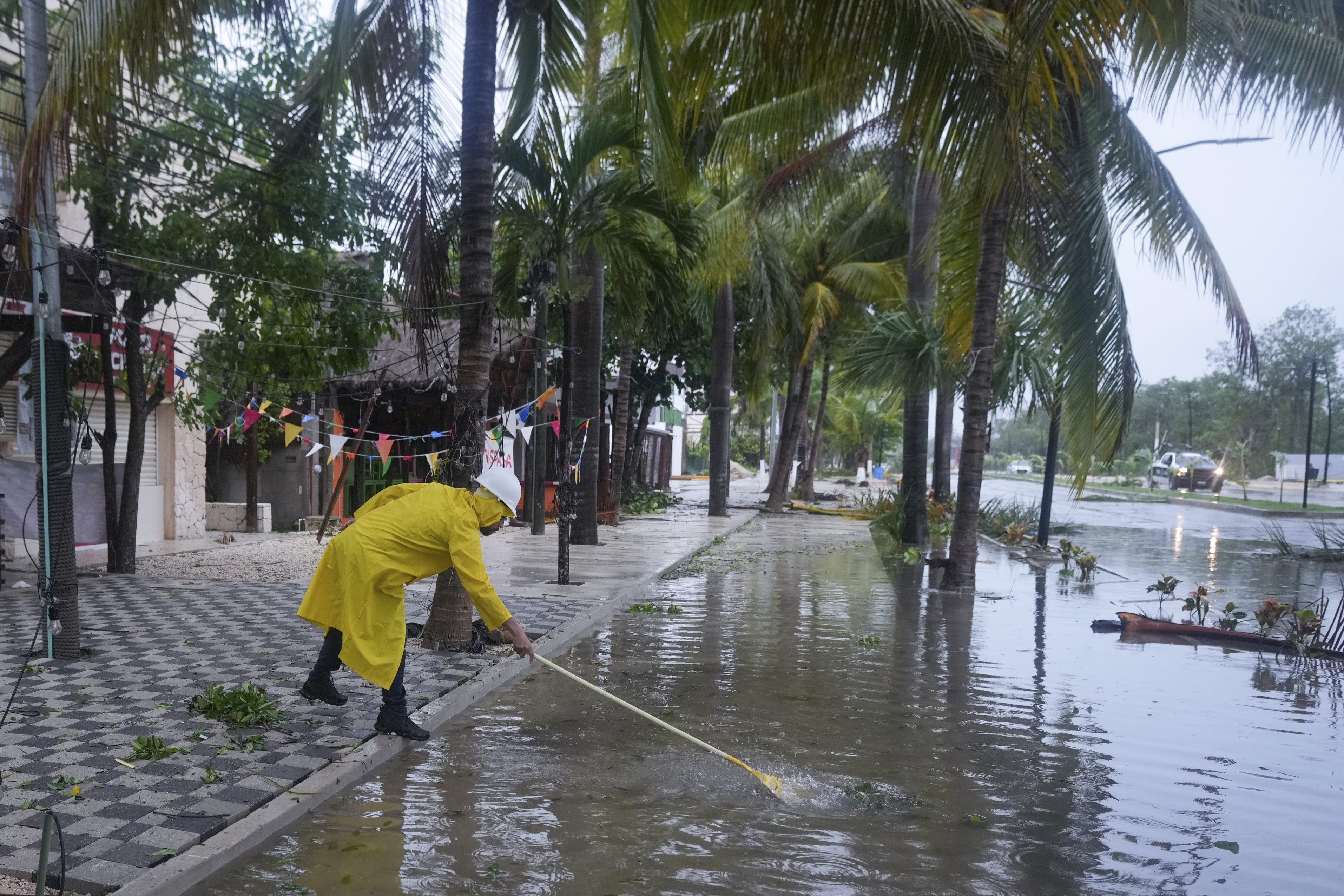 A man unclogs a drain in the aftermath of Hurricane Beryl, in Tulum, Mexico, Friday.