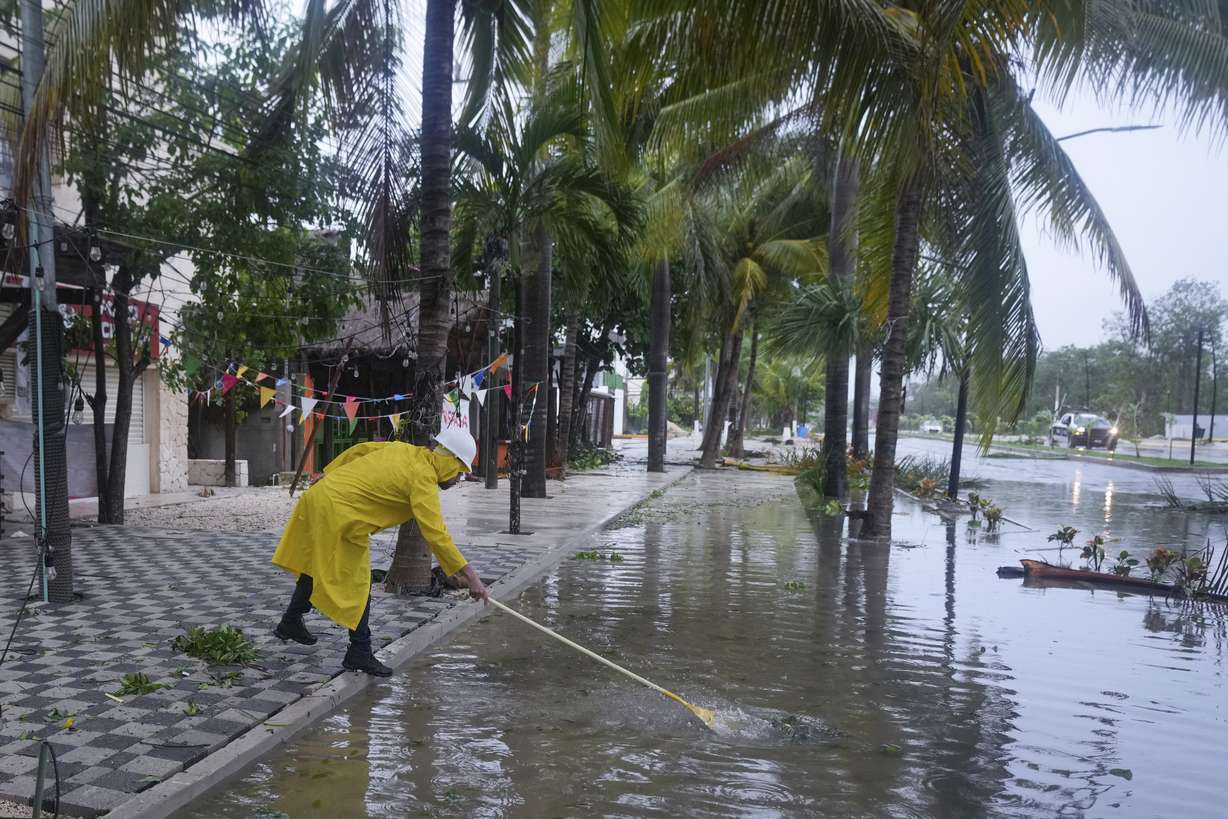 A man unclogs a drain in the aftermath of Hurricane Beryl, in Tulum, Mexico, Friday.