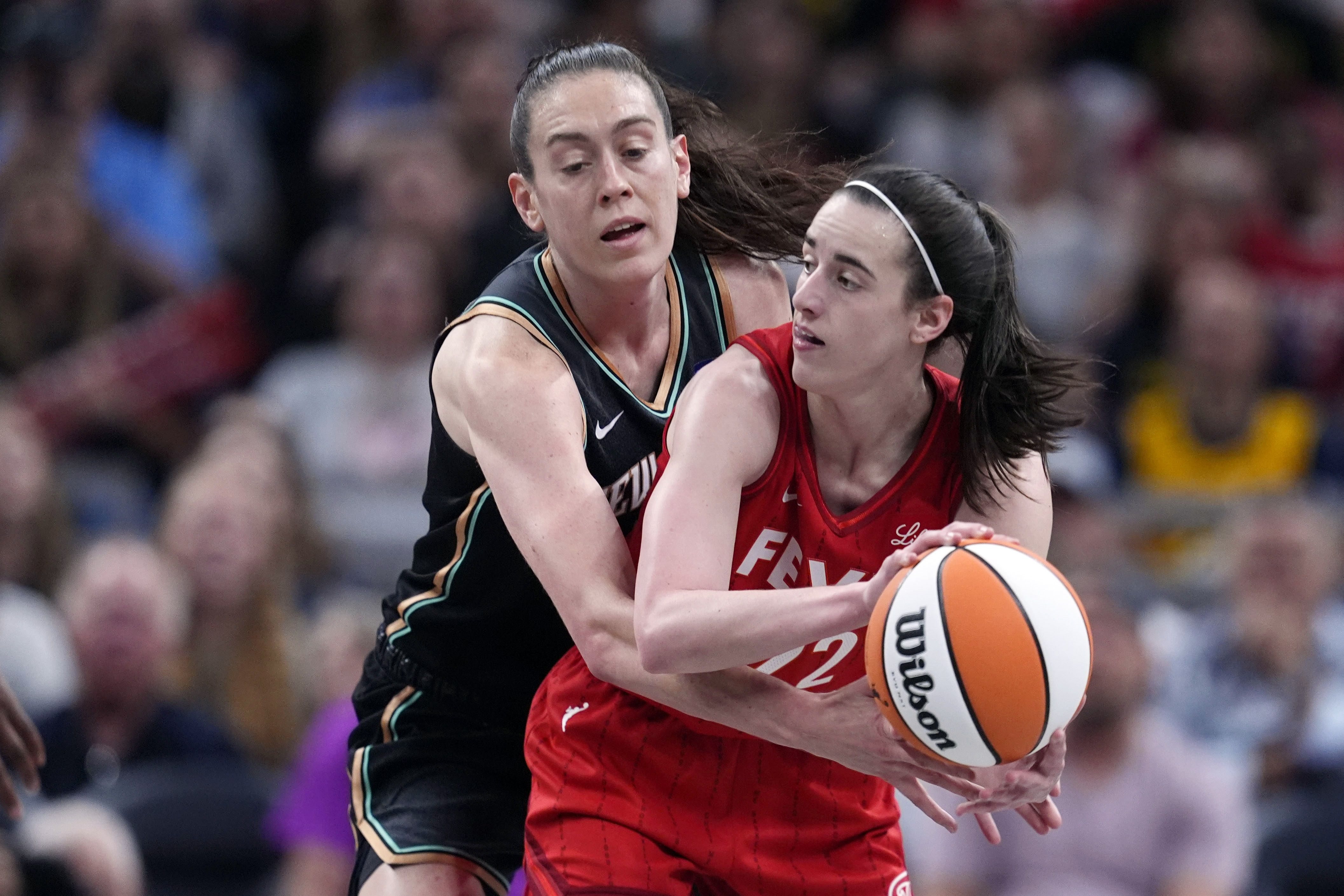Indiana Fever's Caitlin Clark (22) makes a pass as New York Liberty's Breanna Stewart (30) defends during the first half of a WNBA basketball game, Saturday, July 6, 2024, in Indianapolis. 