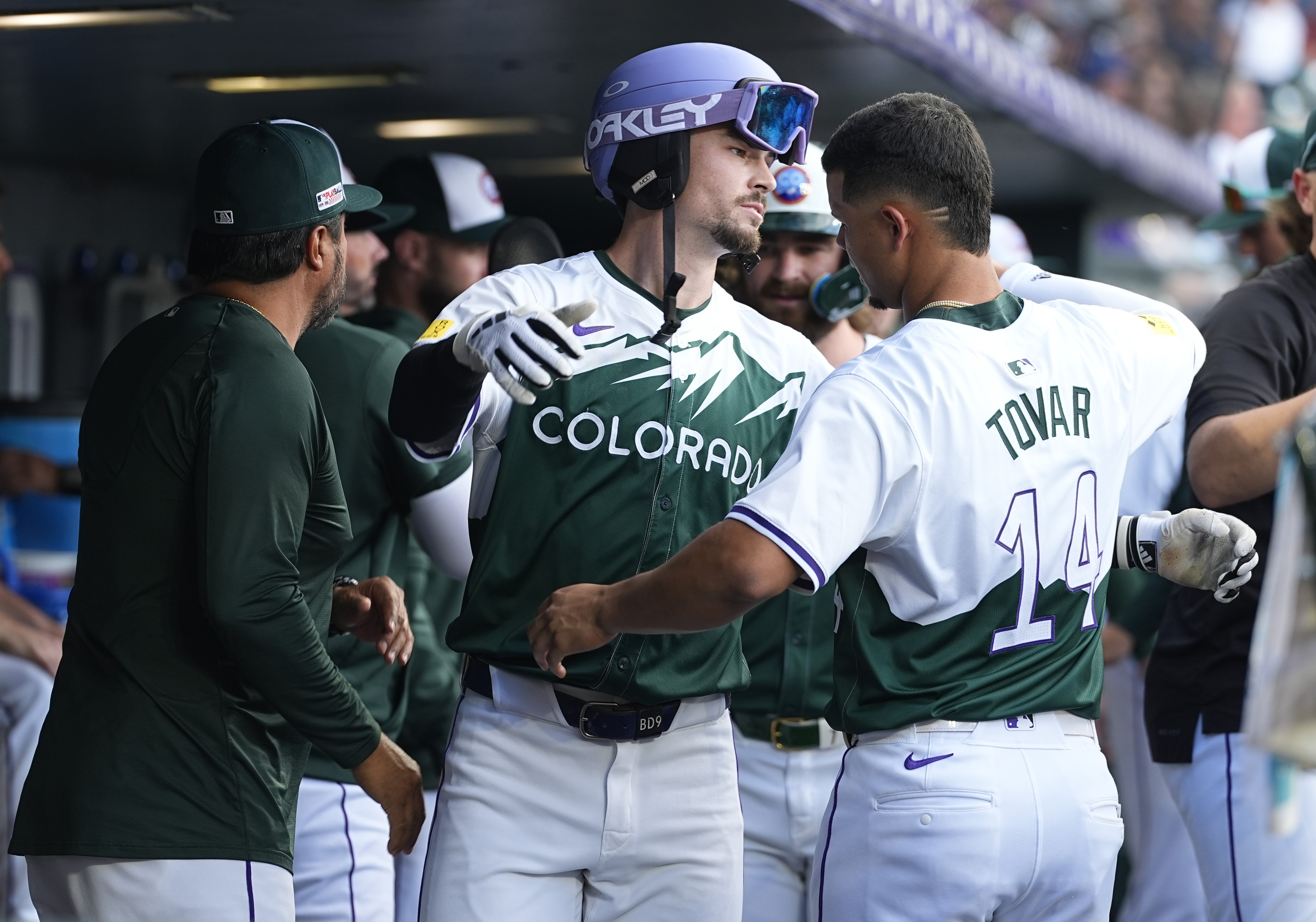 Colorado Rockies' Brenton Doyle, center, hugs Ezequiel Tovar as Vinny Castilla, special assistant to the general manager, looks on as Doyle returns to the dugout after hitting a teo-run home run off Kansas City Royals starting pitcher Seth Lugo in the second inning of a baseball game Saturday, July 6, 2024, in Denver. 