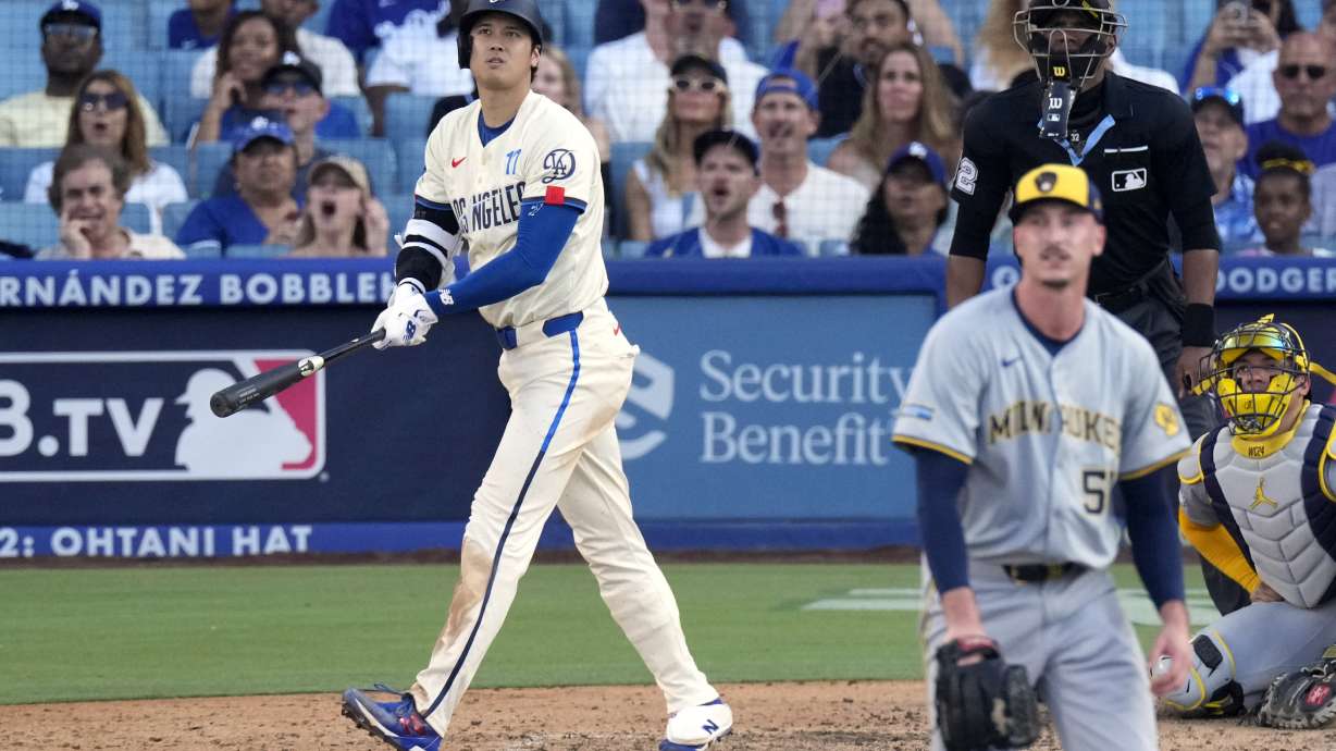 Los Angeles Dodgers' Shohei Ohtani, left, heads to first for a solo home run as Milwaukee Brewers relief pitcher Bryan Hudson, second from left, and catcher William Contreras, right, watch along with home plate umpire Edwin Moscoso during the eighth inning of a baseball game Saturday, July 6, 2024, in Los Angeles.