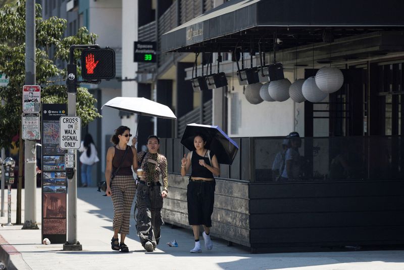 People hold an umbrella to protect themselves from the sun in Little Tokyo during hot weather in Los Angeles, California, on Friday. A widespread heat wave is expected to deliver a fresh batch of record temperatures along the U.S. West Coast, as millions of Americans sweat through a heat dome that is also hovering over Arizona and Nevada.