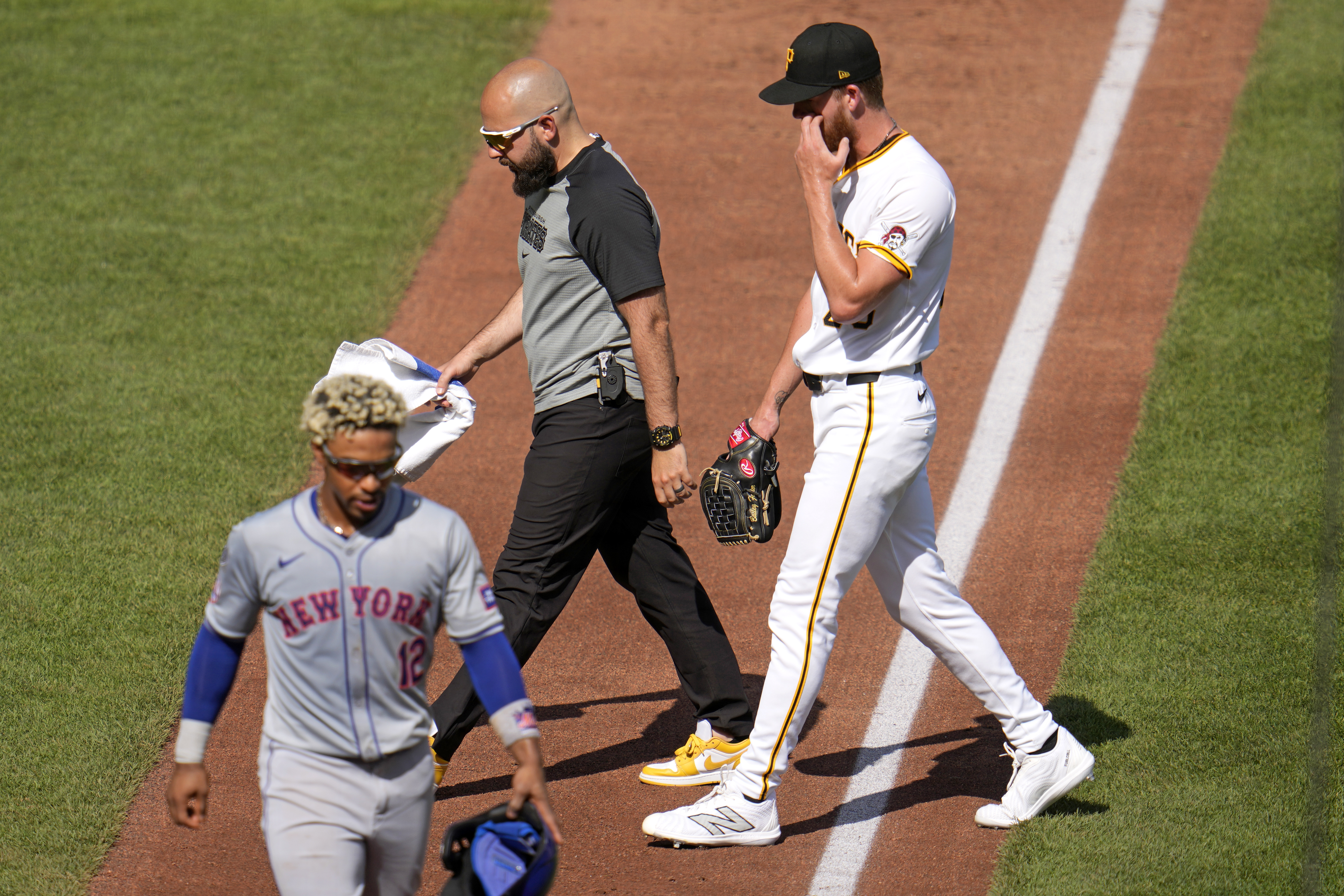 Pittsburgh Pirates starting pitcher Bailey Falter, right, walks to the dugout with a team trainer after removing himself in the third inning of a baseball game against the New York Mets in Pittsburgh, Saturday, July 6, 2024. 