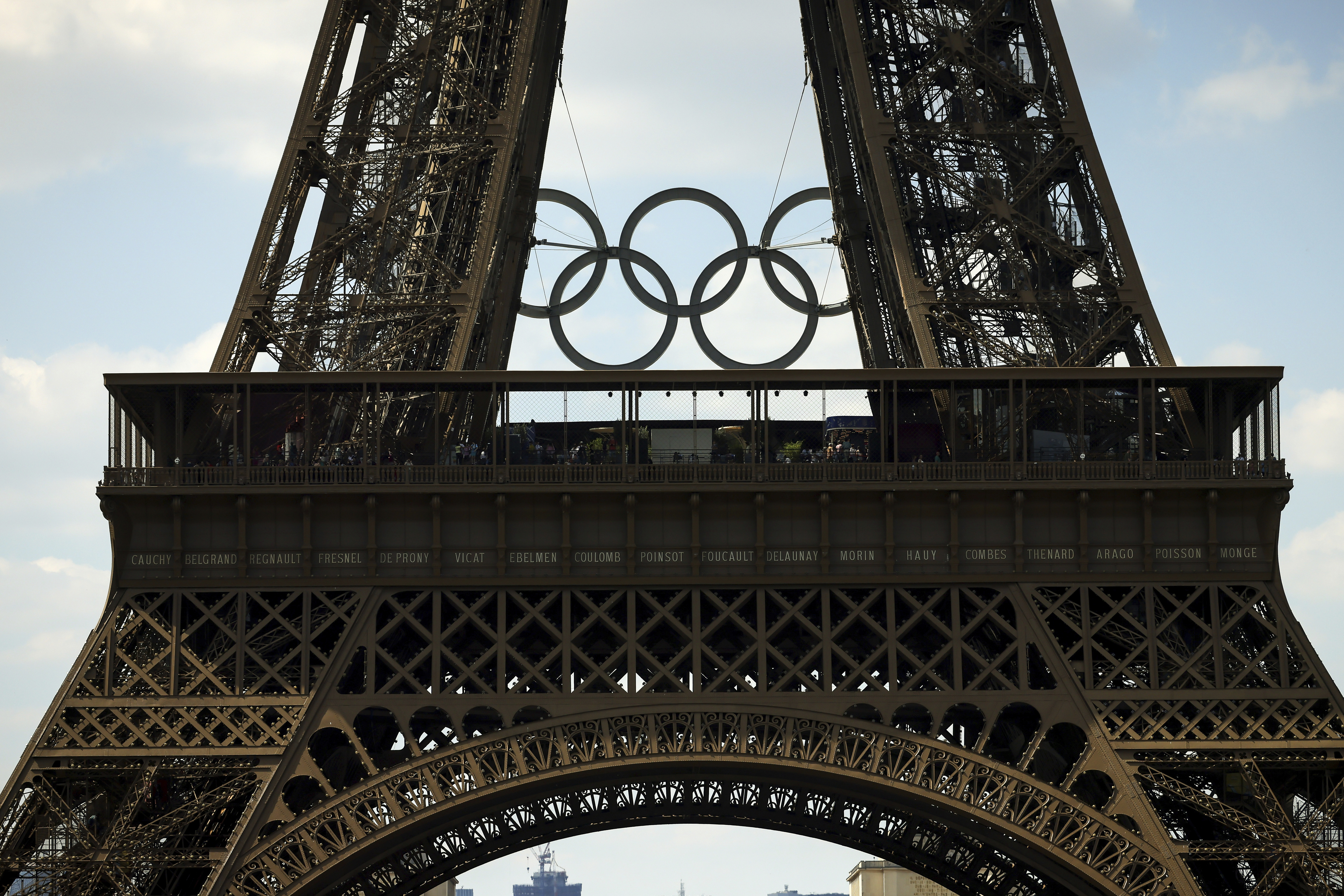 The Olympic rings are seen on the Eiffel Tower from the Beach Volleyball court at the Eiffel Tower stadium, Tuesday, June 25, 2024 in Paris. 
