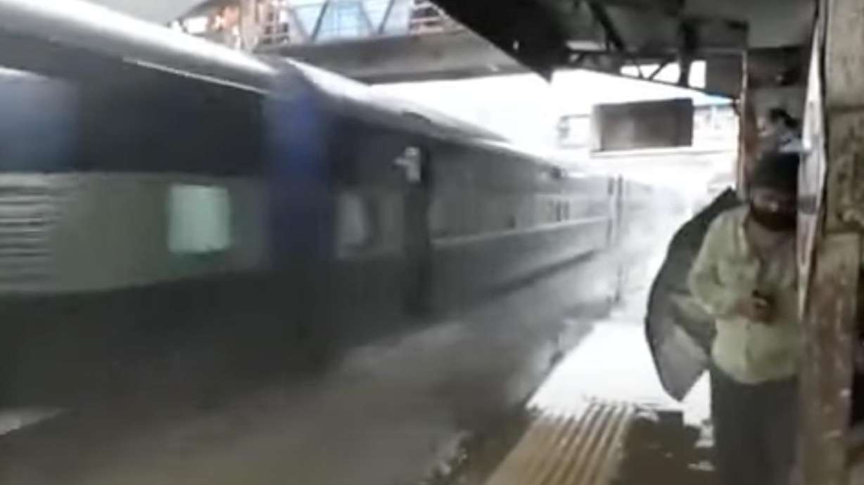 An inbound train splashes passengers waiting at the station.