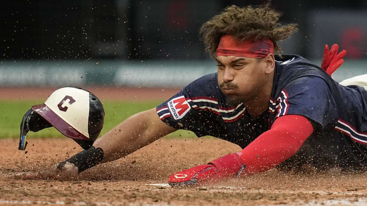 Cleveland Guardians' Josh Naylor slides head first into first base to score in the sixth inning of a baseball game against the Chicago White Sox, Tuesday, July 2, 2024, in Cleveland.