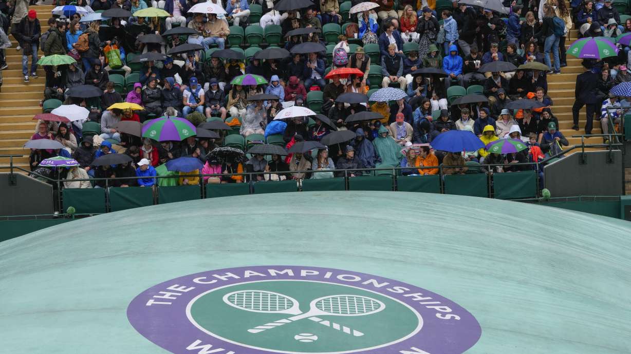 Spectators wait on an outside court as rain delays the start of play at the Wimbledon tennis championships in London, Saturday, July 6, 2024.