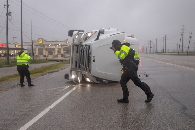 Police officers struggle with fierce winds from Hurricane Beryl as they search an overturned semi-trailer truck for occupants in Freeport, Texas, Monday.