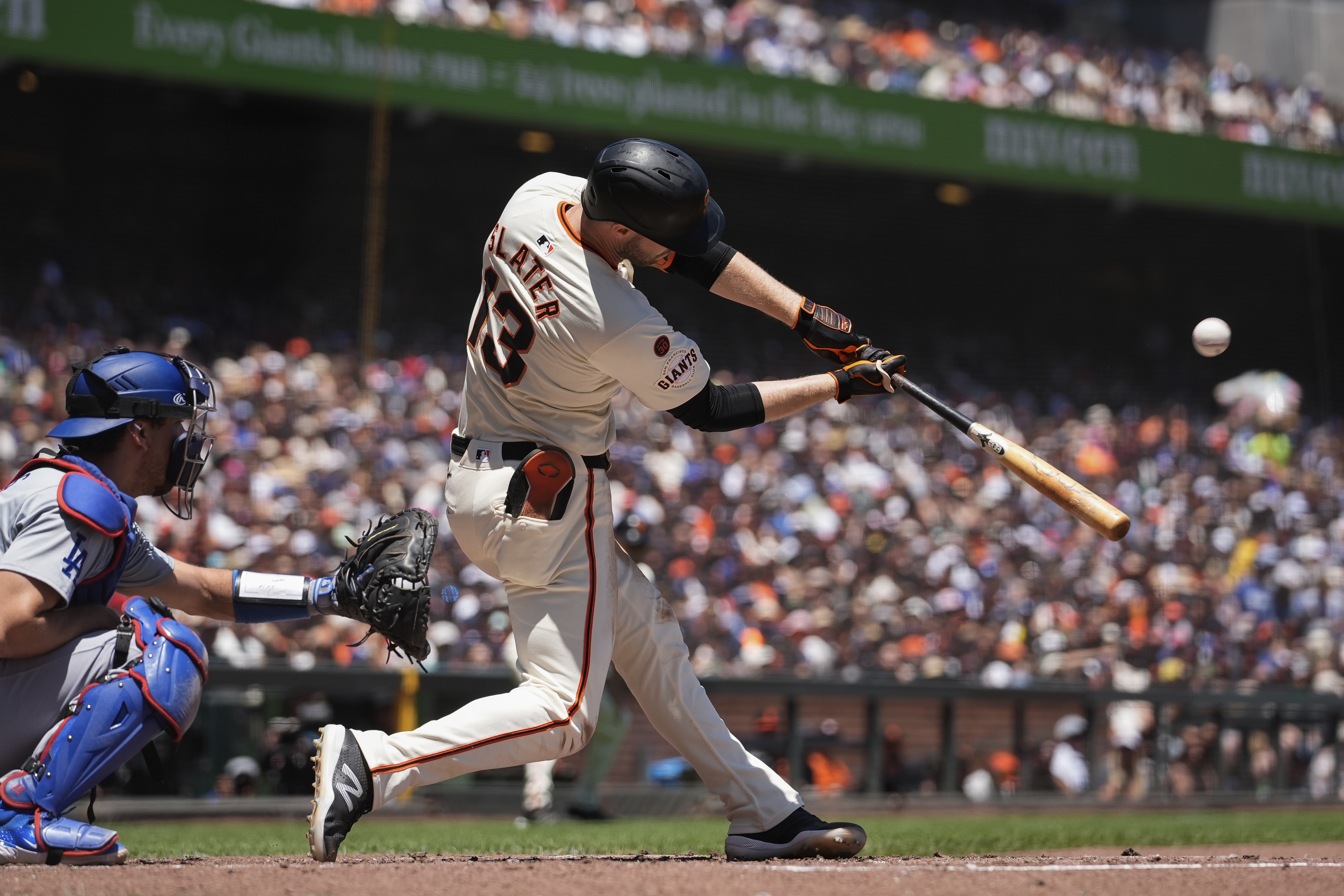 San Francisco Giants' Austin Slater, right, hits a sacrifice fly against the Los Angeles Dodgers during the second inning of a baseball game Sunday, June 30, 2024, in San Francisco. 