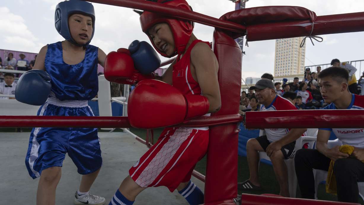 Twelve-year-old Gerelt-Od Kherlen, in red, defends against an attack from his opponent during a bronze medal boxing match on Sukhbaatar Square in Ulaanbaatar, Mongolia, Tuesday, July 2, 2024. Growing up in a Ger district without proper running water, Gerelt-Od fetched water from a nearby kiosk every day for his family. Carrying water and playing ball with his siblings and other children made him strong and resilient.