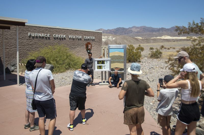 Tourists take photos in front of the Furnace Creek visitor center thermometer Monday, in Death Valley National Park, Calif.