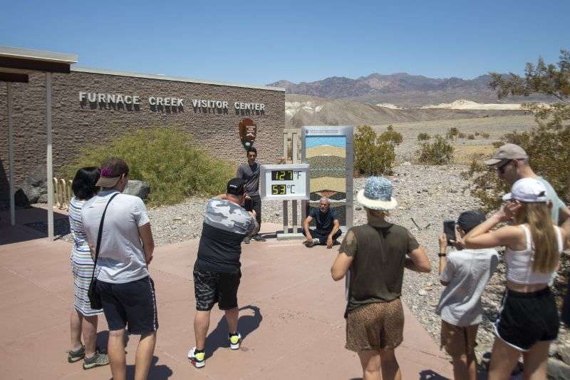 Tourists take photos in front of the Furnace Creek visitor center thermometer Monday, in Death Valley National Park, Calif.