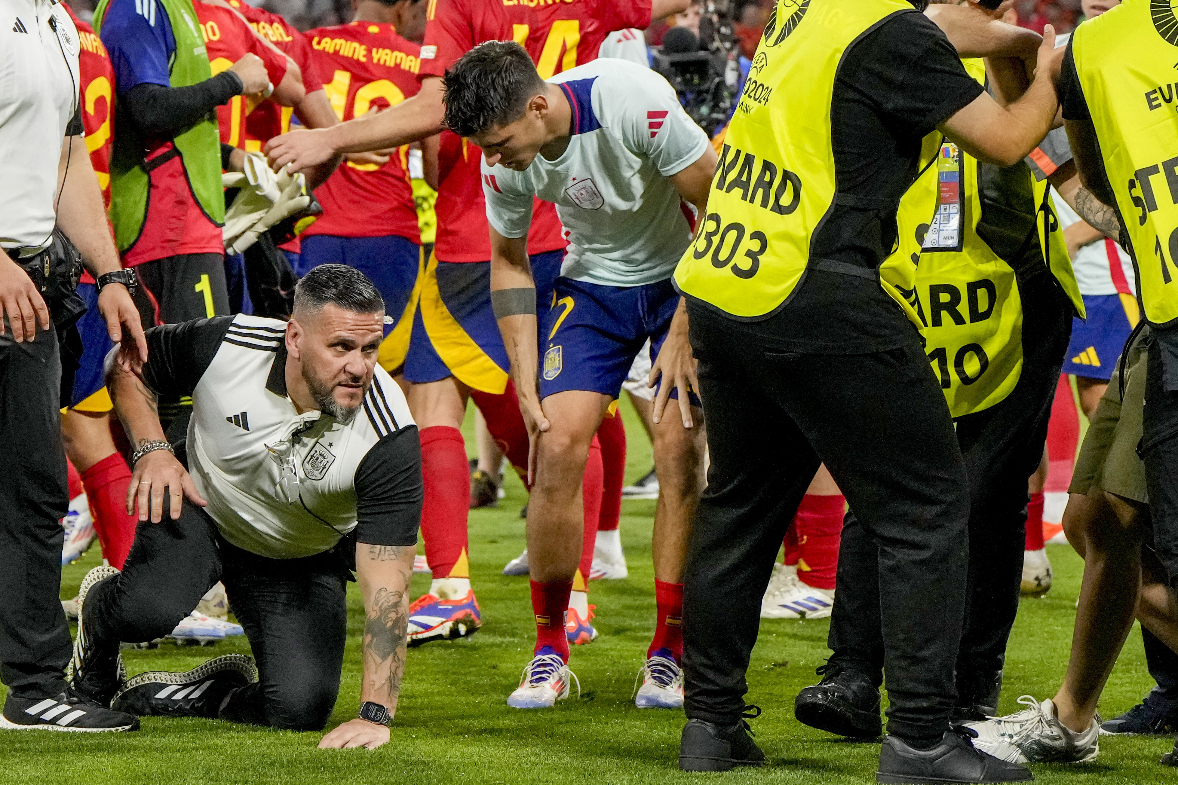 Spain's Alvaro Morata, centre, holds his leg after an incident with an invader after a semifinal match between Spain and France at the Euro 2024 soccer tournament in Munich, Germany, Tuesday, July 9, 2024. Left Spain's Rodri. 