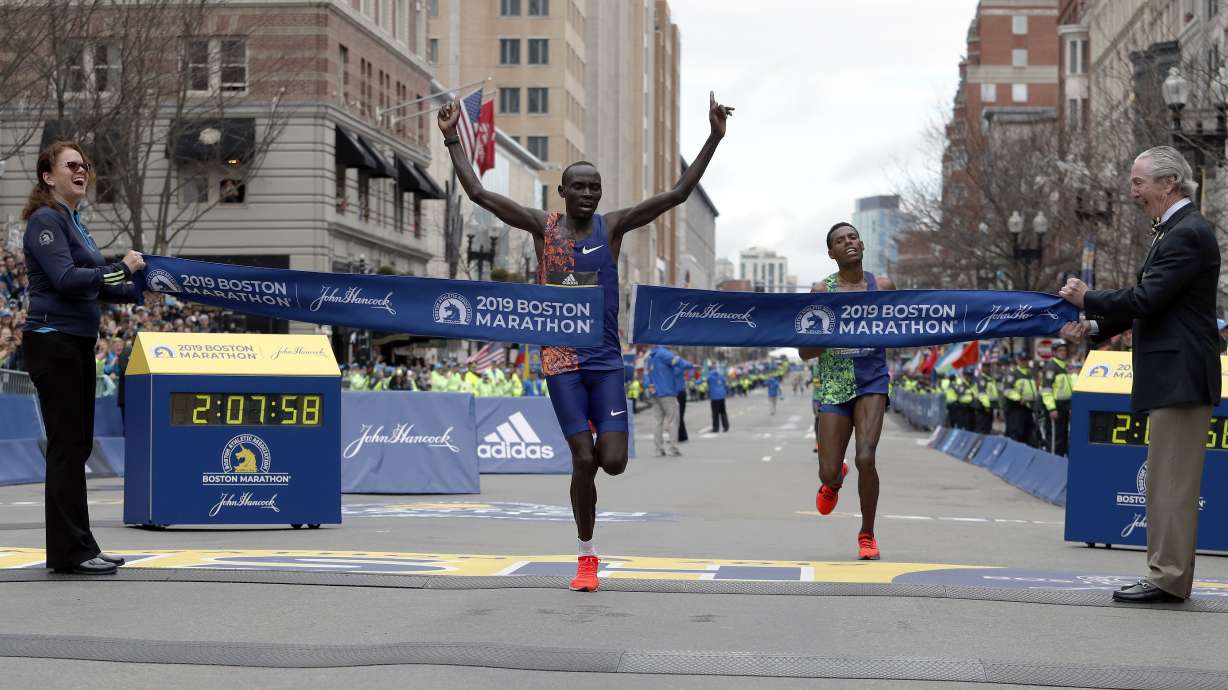 FILE - Lawrence Cherono, of Kenya, breaks the tape to win the 123rd Boston Marathon in front of Lelisa Desisa, of Ethiopia, right, on Monday, April 15, 2019, in Boston. Cherono, a Kenyan runner who won the Boston and Chicago marathons has been banned for seven years for doping and trying to use fake documents to explain his failed drug test, the Athletics Integrity Unit said Wednesday July 10, 2024.